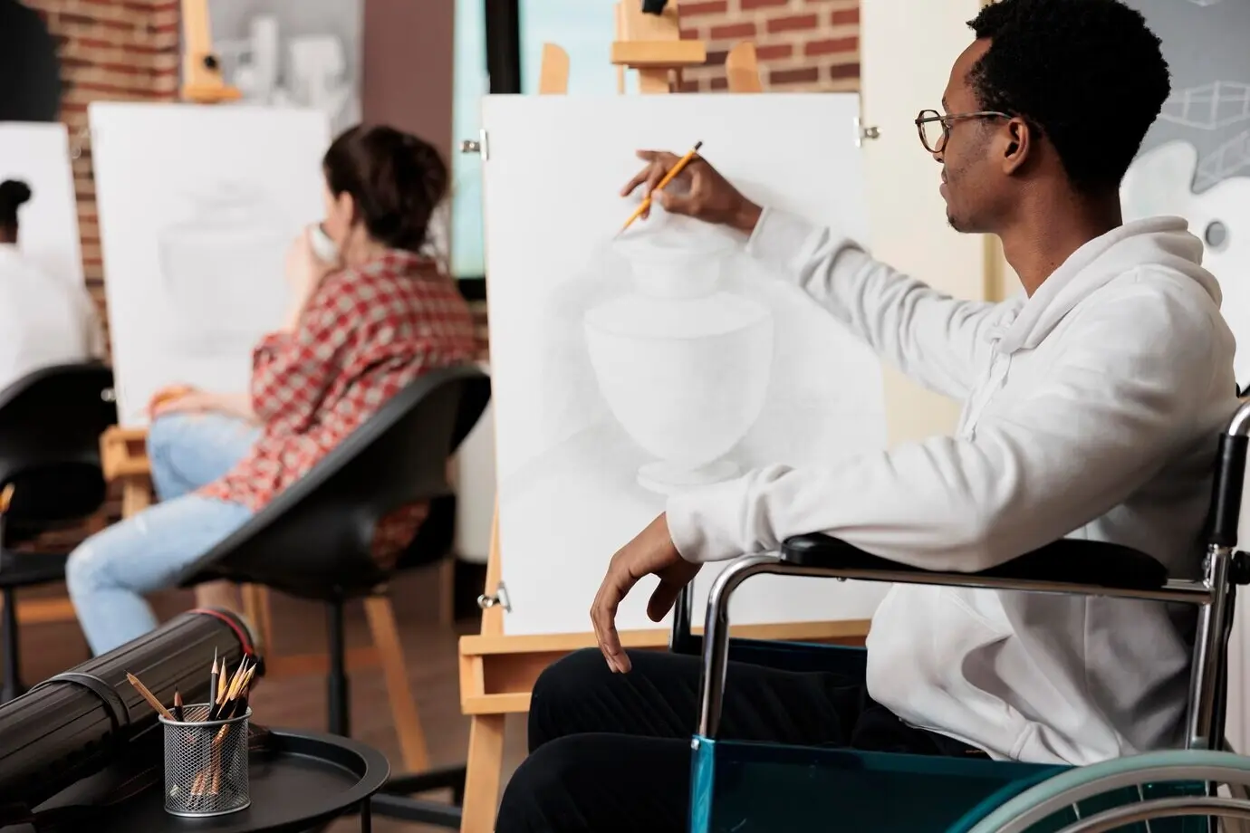 Aficiones creativas para adultos con discapacidad. Hombre afroamericano con discapacidad que usa silla de ruedas dibuja en un estudio de arte, explorando su creatividad, descubriendo nuevas pasiones y aumentando su confianza en sí mismo.